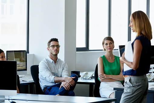 Professionals listening to team leader in office