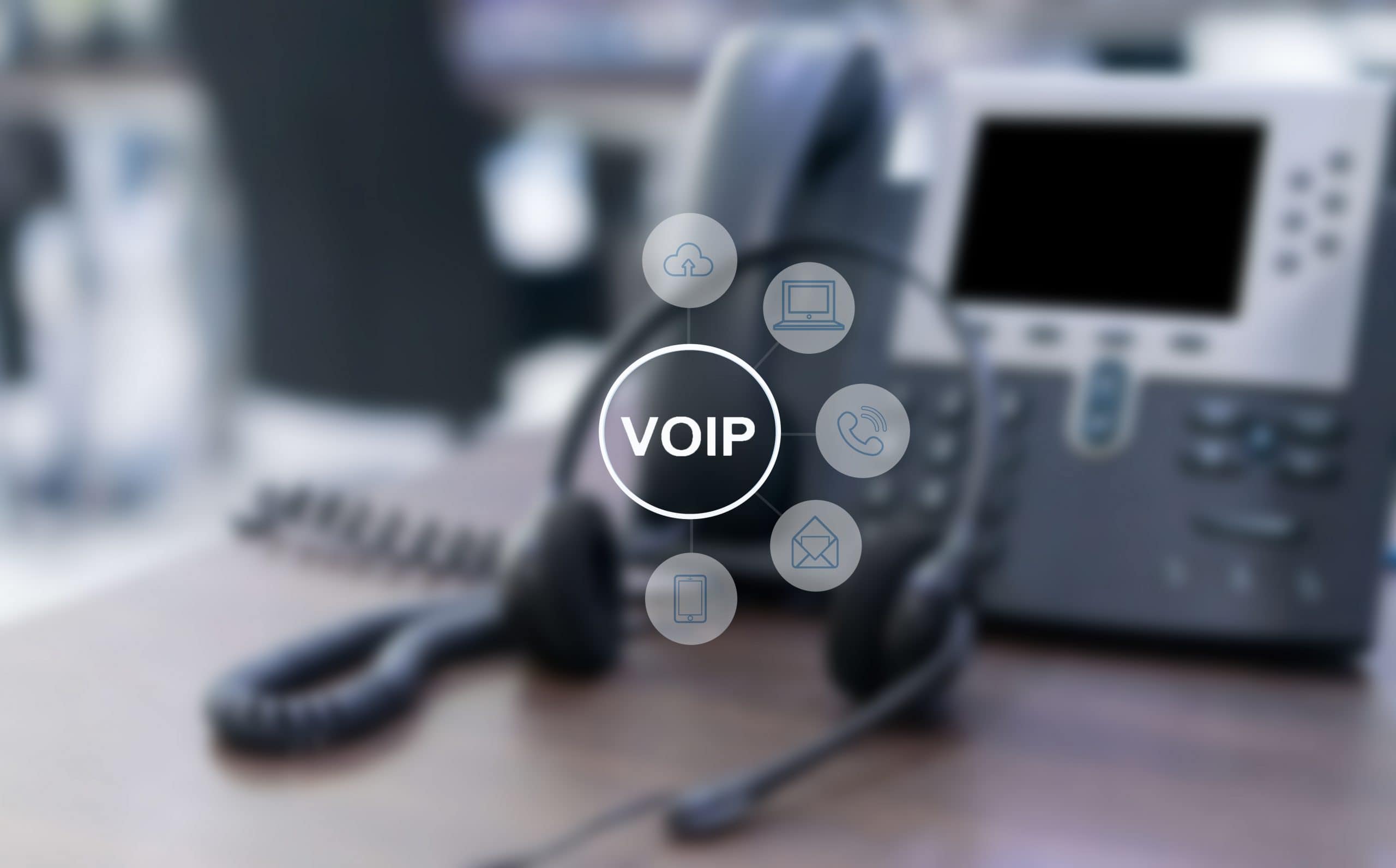 Central VOIP icon with connected telecom icons on a blurred office desk area.