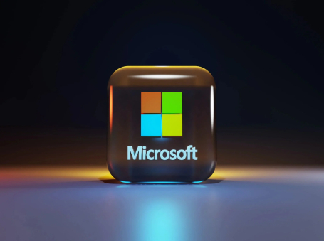 Glossy 3D cube with the colorful Microsoft logo and the word 'Microsoft', glowing on a dark background.